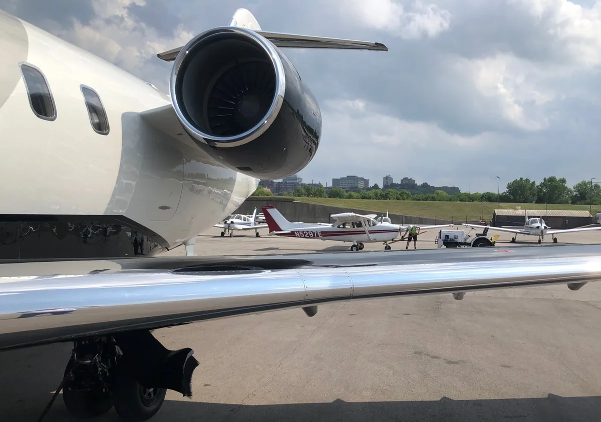 Close view of a business jet engine and wing on an airport ramp.