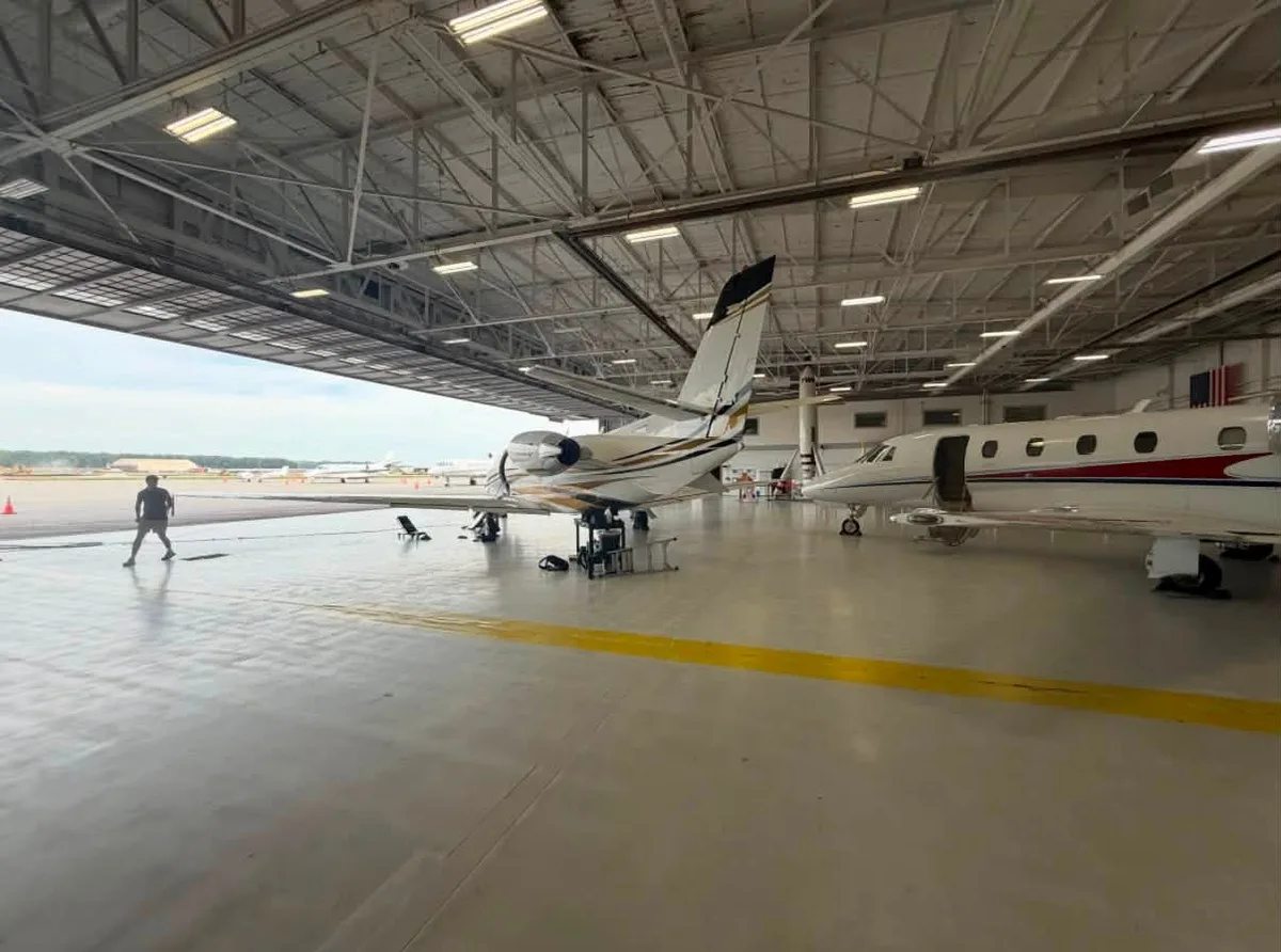 Aircraft inside a large hangar with an open hangar door.