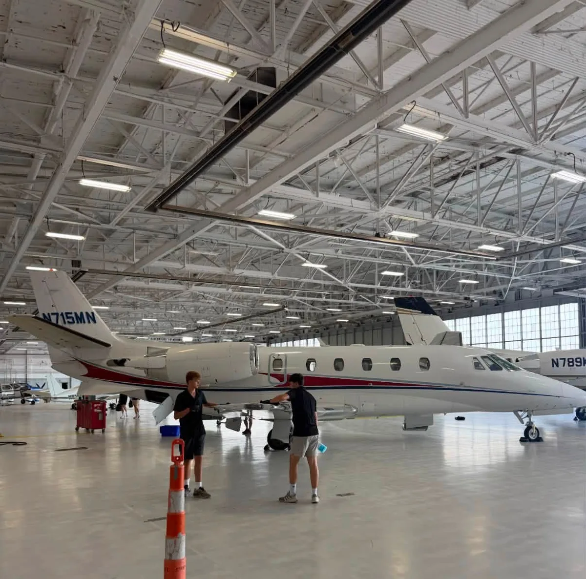 Aircraft and two people inside a hangar.