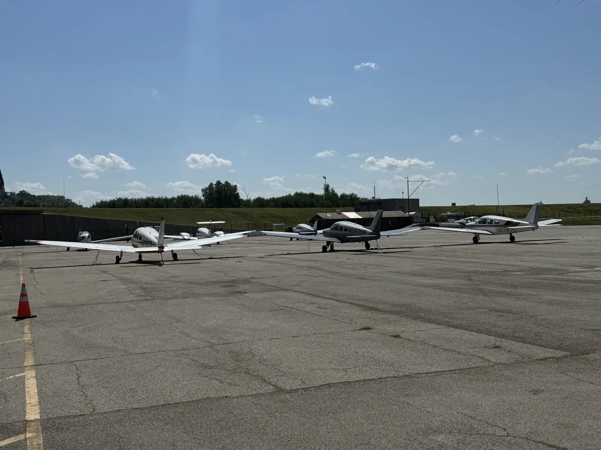 Several small aircraft parked on an airport ramp.